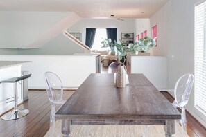 A dining area with a wooden table, clear chairs, and a vase with greenery. - Urban Luxe Escape - Stylish & Serene (Houston)