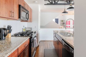 A modern kitchen with granite countertops, stainless steel appliances, and wooden cabinets. - Urban Luxe Escape - Stylish & Serene (Houston)