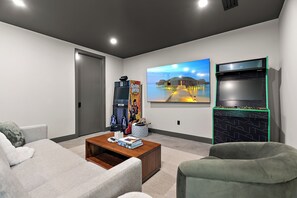 Ein modernes Wohnzimmer mit Flachbildfernseher, Couch, Couchtisch mit Büchern und einer Spielkonsole.