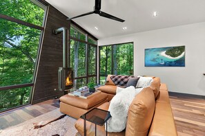 Ein modernes Wohnzimmer mit großem Fenster, Kamin, einer Couch und einem Bild einer tropischen Insel.