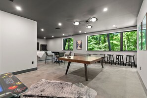 Ein modernes Interieur mit Tischtennisplatte, Stühlen und großen Fenstern mit Blick auf Grünflächen.