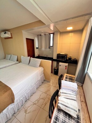 A hotel room with a bed, a small kitchenette, and a dining area with a table and chairs. - Porto Beach Flats Dolce Vita Piscina  (Ipojuca)