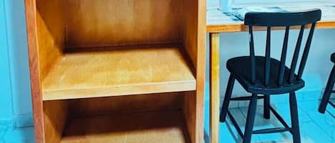 Une bibliothèque en bois à trois étagères, une chaise noire et un bureau avec un ordinateur.