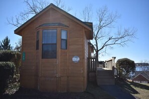 A small wooden cabin with a dormer window, a front door, and a small porch area. - Acadian Shores Cabins - Lake View Cabin 4 (Zwolle)