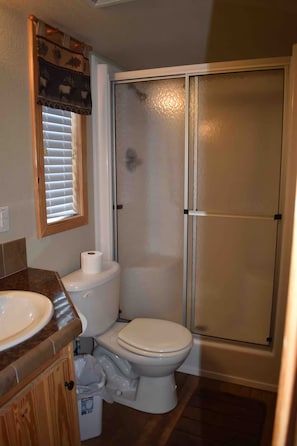 A bathroom with a toilet, a sink, and a shower enclosure. - Acadian Shores Cabins - Lake View Cabin 4 (Zwolle)