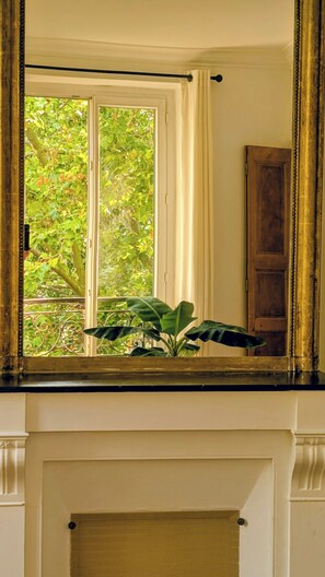 Ein Zimmer mit Fenster, einer Pflanze auf der Fensterbank und einer Holztür.