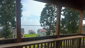 A wooden deck with a view of a lake and houses in the background.