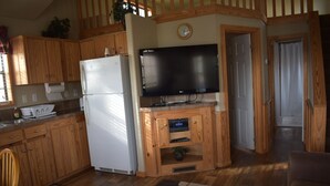 A kitchen with wooden cabinets, a white refrigerator, a flat-screen TV, and a built-in radio.