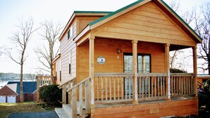 A wooden cabin with a porch, a visible door, and a small window.