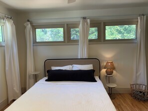 Une chambre à coucher avec un lit, une lampe de chevet, une petite table et un panier en osier.