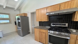 A kitchen with wooden cabinets, a stainless steel refrigerator, a gas stove, and a built-in oven. - Spacious Ranch on Large Lot W Ample Parking (Wichita)