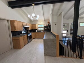 A modern kitchen with wooden cabinets, a built-in oven, and a large island with a sink. - Spacious Ranch on Large Lot W Ample Parking (Wichita)