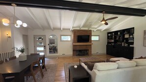 A spacious living room with a fireplace, a dining area with a table and chairs, a sofa, and a bookshelf. - Spacious Ranch on Large Lot W Ample Parking (Wichita)