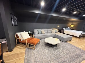 A modern bedroom with a grey sectional sofa, a wooden chair, a small table, and a bed with a nightstand. - Spacious Ranch on Large Lot W Ample Parking (Wichita)