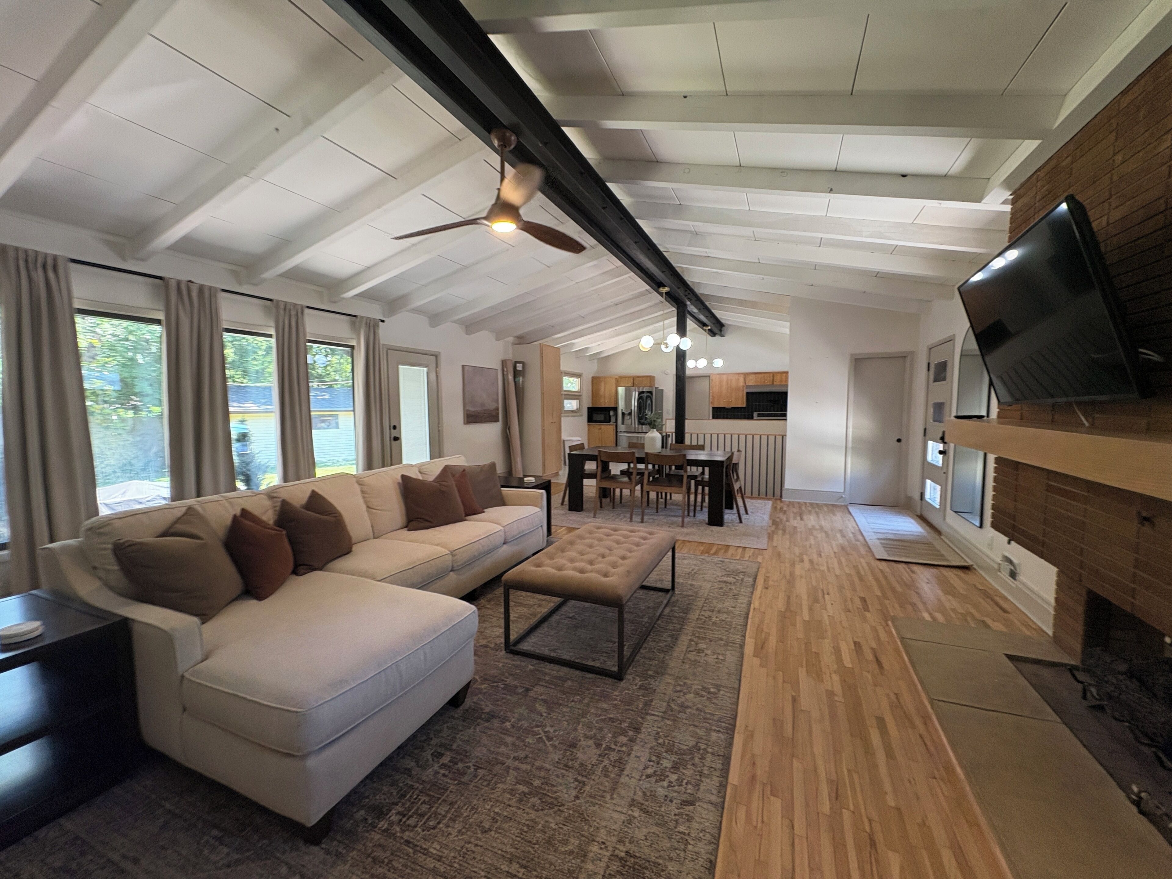 Ein modernes Wohnzimmer mit einem Ecksofa, einem an der Wand befestigten Fernseher und einem Deckenventilator.