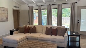 A living room with a sectional sofa, an ottoman, and a side table. - Spacious Ranch on Large Lot W Ample Parking (Wichita)