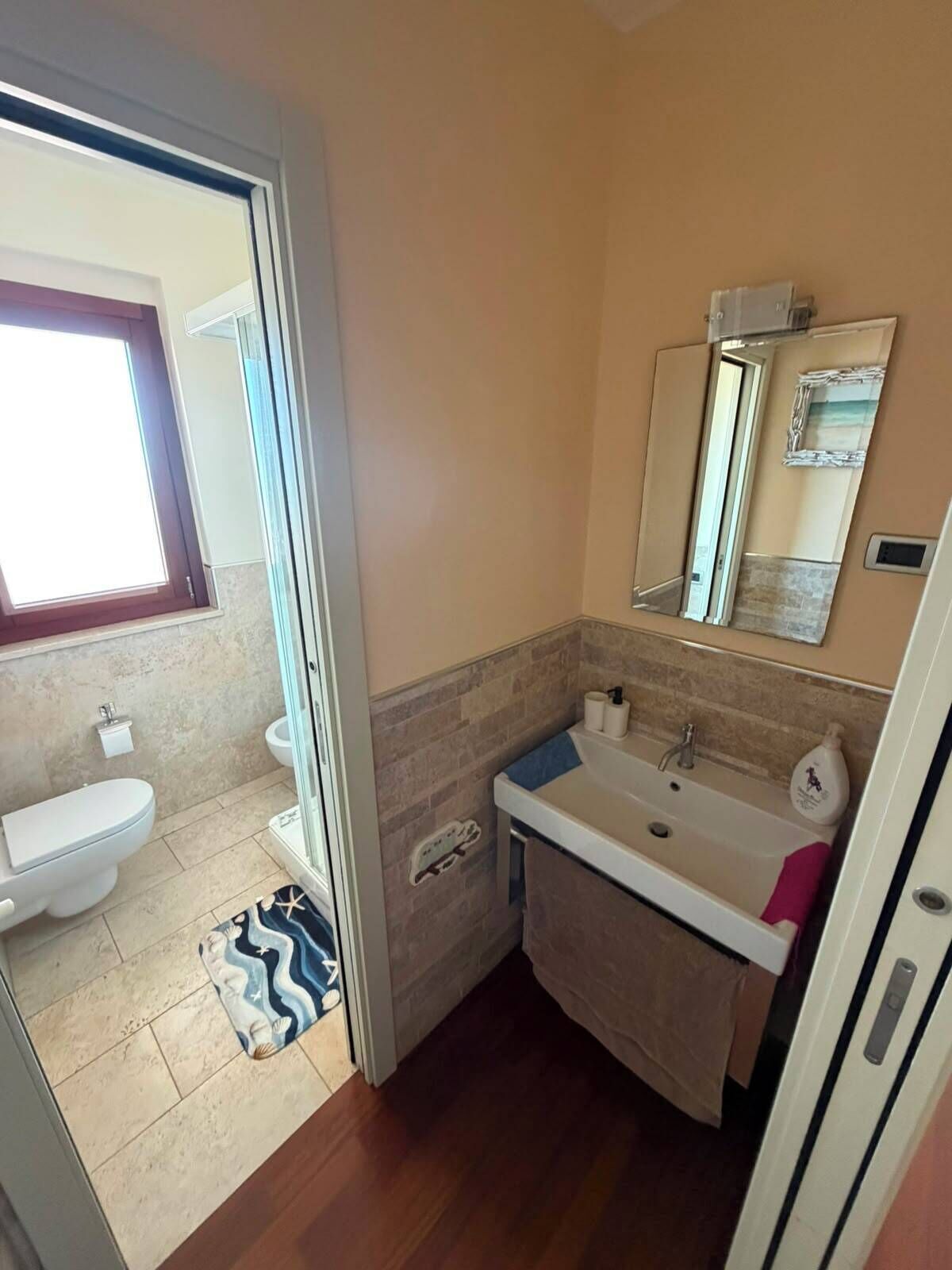 Et badeværelse med toilet, vask og brusebad.