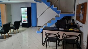 A modern interior with a staircase, a refrigerator stocked with beverages, and a bar area with chairs. - Hostel Way Fortaleza (Fortaleza)