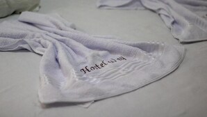 A bed with a white sheet and a towel with 'Hostel Way' embroidered on it. - Hostel Way Fortaleza (Fortaleza)