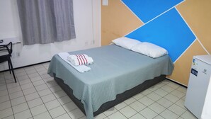 A hotel room with a bed, a chair, a small table, and a wall unit with a power outlet. - Hostel Way Fortaleza (Fortaleza)