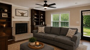 Ein Wohnzimmer mit Kamin, einer Couch, einem Hocker und einem Deckenventilator.