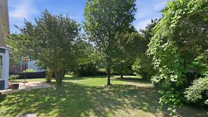 Ein Garten mit Rasen, Bäumen und einem Basketballkorb.