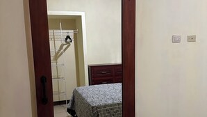Et værelse med seng, garderobe og spejl.