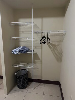 A storage closet with shelves and a hanging rack.