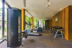 Ein Fitnessstudio mit Cardiogeräten, Kraftmaschinen und einer Hantelbank.