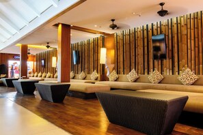 A modern lobby with a long reception desk, a sofa area with patterned cushions, and a bamboo wall design. - Holiday Inn Resort Phuket Surin Beach (Choeng Thale)
