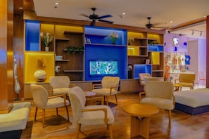 A modern hotel lobby with a TV, comfortable seating, and a variety of plants and decorations. - Holiday Inn Resort Phuket Surin Beach (Choeng Thale)