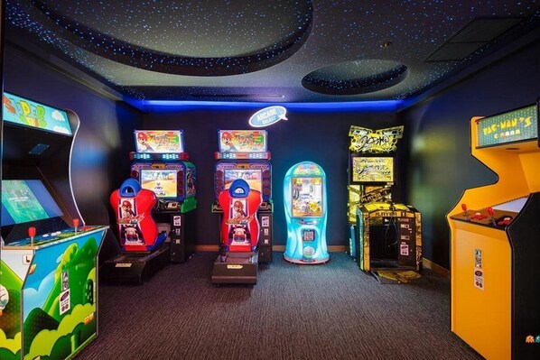 A room with arcade games, including a Pac-Man machine, and a neon sign. - Holiday Inn Resort Phuket Surin Beach (Choeng Thale)