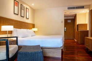 A hotel room with a bed, two bedside lamps, a chair, a small table, and a wardrobe. - Holiday Inn Resort Phuket Surin Beach (Choeng Thale)