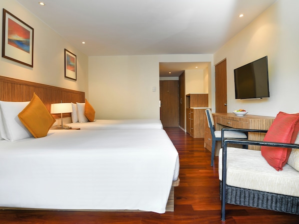 Habitació d'hotel amb dos llits, un escriptori, una cadira, un televisor i un quadre a la paret.