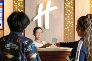 Una zona de recepció amb un taulell de fusta i un gran cartell amb la lletra 'H' il·luminada.