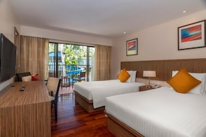 A hotel room with two beds, a desk, a chair, a TV, and a balcony with a pool view. - Holiday Inn Resort Phuket Surin Beach (Choeng Thale)