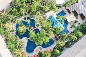 An aerial view of a resort with multiple swimming pools, palm trees, and lounge areas. - Holiday Inn Resort Phuket Surin Beach (Choeng Thale)