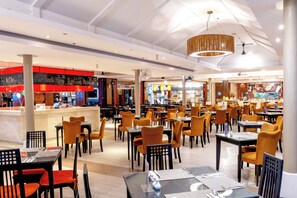 Un restaurant ampli amb diverses taules i cadires, una barra amb menú, i un disseny de sostre modern.