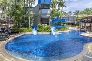 Una piscina con un edificio moderno y palmeras al fondo.