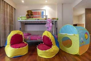 Una cama litera infantil con dos osos de peluche, una carpa de juegos y dos pufs.
