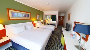 Een hotelkamer met twee bedden, een bureau met een computer en een televisie.
