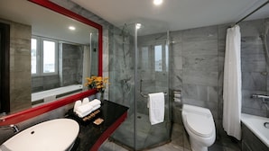 A modern bathroom with a glass-enclosed shower, a white toilet, a large mirror with a red frame, and a black countertop with toiletries. - Grand Minerva Hotel (Hanoi)