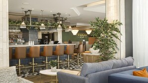 A modern bar area with seating, a reception desk, and a large plant. - Voco Southampton (Southampton)