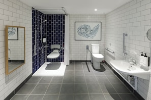A modern bathroom with a shower, toilet, and sink. - Voco Southampton (Southampton)