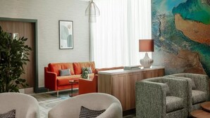 A modern living room with a red sofa, a grey armchair, and a wooden coffee table. - Voco Southampton (Southampton)