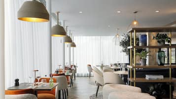 Un comedor moderno con varias mesas, sillas e iluminación colgante.