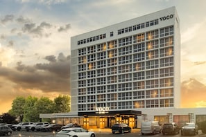A modern hotel building with a grid of windows, a prominent entrance, and a parking lot. - Voco Southampton (Southampton)