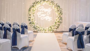 Un pasillo nupcial con sillas blancas y un arco floral con un letrero de neón.