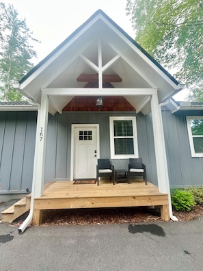 A house with a porch, two chairs, a door, and a window.