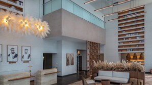 Un vestíbulo moderno con mostrador de recepción, zona de estar, estanterías y plantas decorativas.
